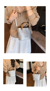 Detailed view of silver woven bucket bag featuring a natural bamboo handle and metal logo