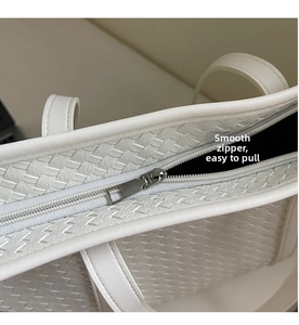 Detailed macro view of the smooth silver zipper and woven texture on white tote bag