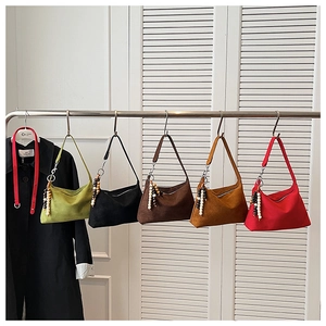A row of colorful suede-style underarm bags hanging on a rack for fashion display.