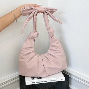 Pink bow-decorated crossbody dumpling bag with soft pleated design and knotted handle