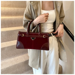 Detail of vintage burgundy tote bag with triangular plaque and mixed leather textures