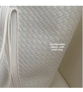 Close-up of the fine woven texture on a minimalist cream tote bag made of soft PU leather