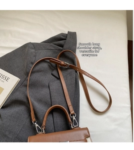 Detailansicht einer karamellbraunen Umhängetasche aus Leder auf einem grauen Blazer für Damen