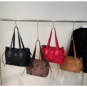 Hanging display showing four suede tote bags in black, dark brown, red, and light brown