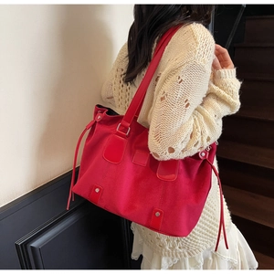 Detail of red matte leather tote bag with silver studs and tassel on a female model