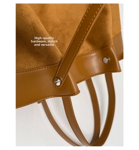 Detail view of brown suede handbag featuring silver metal rivets and precise stitching