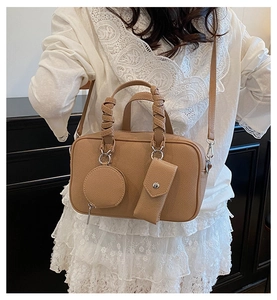 Close-up of khaki Boston bag with detachable mini pouches and woven handle shown on model