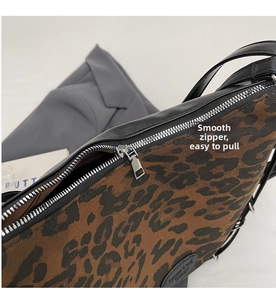 Detail shot of the smooth metal zipper and leopard print texture on a tote bag