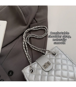 Detailed macro view of silver quilted bag with metallic chain strap and twist lock
