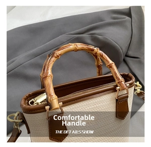 Detail of woven straw bucket bag showing wood handle and golden metal hardware