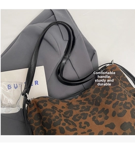 Close-up of leopard print canvas bag featuring black leather straps and metal hardware