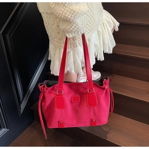 Detail of red suede tote bag with fringe tassel on wooden stairs in a vintage style