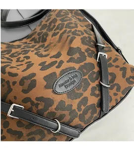 Close-up of leopard print canvas bag showing textured fabric and black leather logo strap