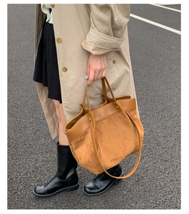 Detail of contrast stitching and suede texture on a large capacity tote bag in street style