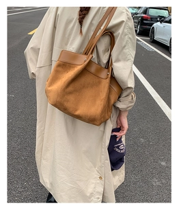 Detailed view of caramel suede and leather tote bag styled on model for street look