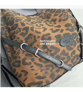 Macro view of leopard print canvas handbag with black leather straps and silver hardware