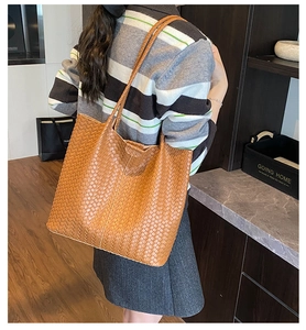 Détail d'un grand sac cabas tressé marron montrant sa texture et sa bandoulière