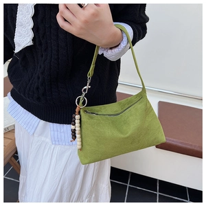 Green suede underarm shoulder bag with chic wooden bead pendant and zipper detail.