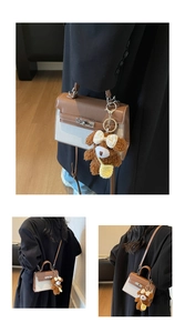 Detail einer braun-beigen Handtasche mit Schloss und Teddybär-Anhänger