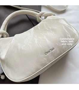 Close-up of marble texture cream leather cloud bag with branded logo and soft round handle
