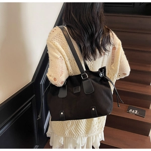 Detail of minimalist black tote bag with silver studs and drawstring in casual setting