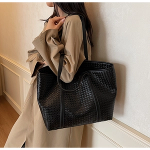 Detail shot of black woven leather tote bag showing large capacity and texture