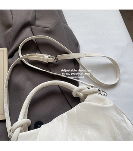 Detail of cream cloud bag featuring adjustable shoulder strap and knotted handle design