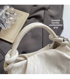 Detail of soft knotted handle and cream pleated leather texture on elegant shoulder bag