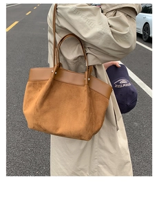 Detail of a large brown suede tote bag with leather straps used in an outdoor setting
