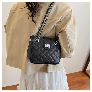 Detail of classic black quilted shoulder bag with silver chain and metal turn-lock