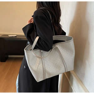 Detail of silver woven leather tote bag showing grid texture and shoulder strap