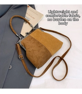 Detail of vintage two-tone kiss-lock handbag with metal handle on a white fabric surface