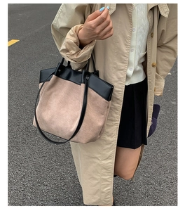 Close-up of beige matte tote bag with black leather trim and long shoulder strap