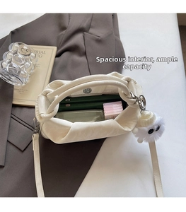 Detail view of cream cloud crossbody bag interior with magnetic closure and charm