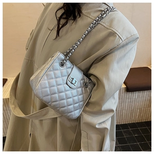 Close-up of quilted silver chain bag featuring metallic texture and turn-lock closure