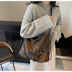 Close-up of leopard print tote bag featuring black leather straps and silver buckle hardware