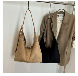 Minimalist suede half-moon tote bags in khaki and black hanging in an autumn setting