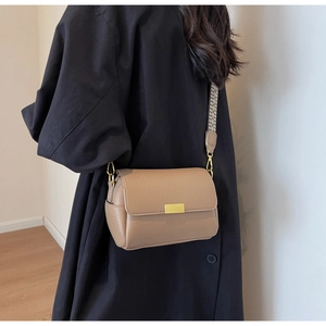 Close-up of brown litchi pattern leather bag with black and white woven strap and metal buckle
