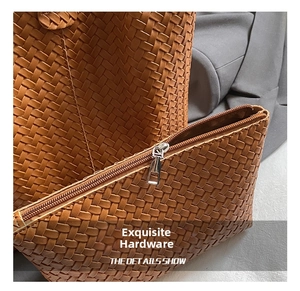 Détail de la texture en cuir tressé et fermeture éclair argentée du sac marron