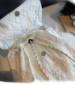 Detail of white quilted nylon backpack with colorful embroidery and drawstrings
