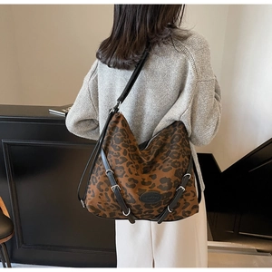 Detail shot of leopard print tote bag with black leather straps and silver buckles