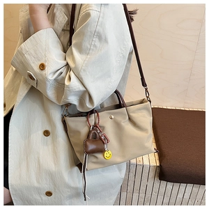 Detail shot of a casual lightweight nylon shoulder bag with cute charms for women daily commute.