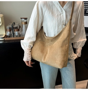 Detail shot of the suede hobo shoulder bag styled by a model in a modern cafe setting
