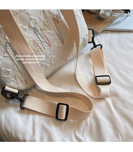 Detail of adjustable beige woven shoulder strap with black buckle on quilted backpack