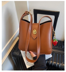 Close-up of brown PU bucket bag with golden twist lock and a cute strawberry charm accessory