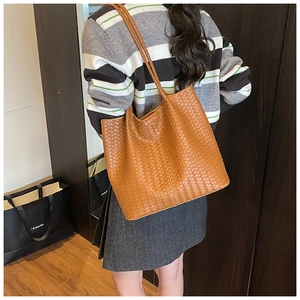 Detailed view of brown woven leather texture on a large capacity tote shoulder bag