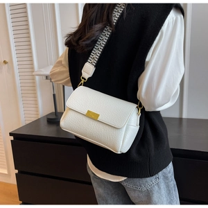 Détail du sac bandoulière blanc à motif litchi avec sangle tissée et ferrures dorées