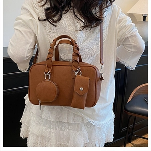 Detail of caramel brown Boston bag with woven handles and small round hanging pouch