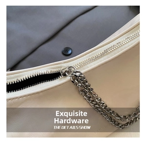 Detailed close-up of the silver zipper and decorative chains on a cream hobo shoulder bag