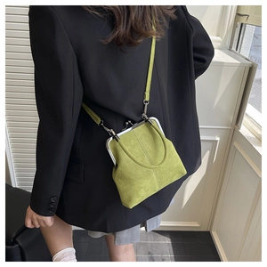Rear view of a model wearing a green suede-textured retro shell bag with a black blazer